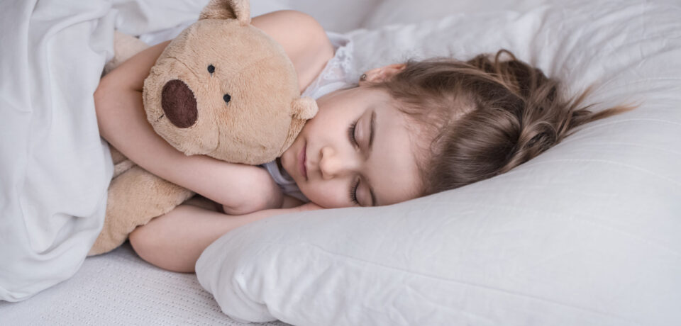 Little cute girl in bed with toy Cute little girl sleeps sweetly in a white cozy bed with a soft bear toy, the concept of children's rest and sleep